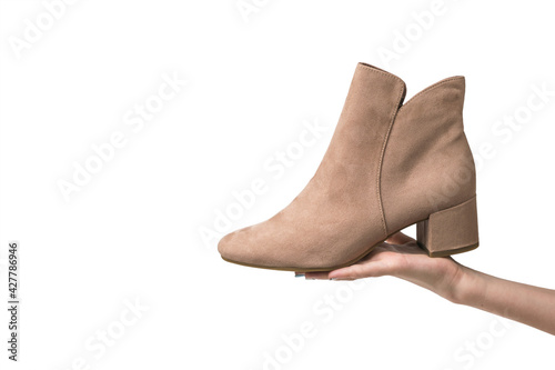 The girl's hand holds a light-colored boot isolated on a white background.