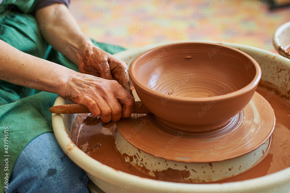 Close-up of the hand of a master potter working on a circle with clay. Master class in the workshop.