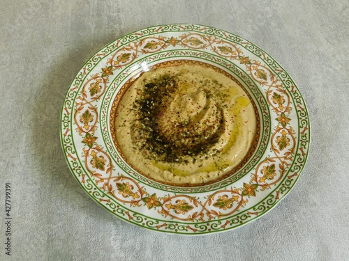 homemade hummus with herbs and olive oil in a traditional oriental dish. vegetarian, healthy food.