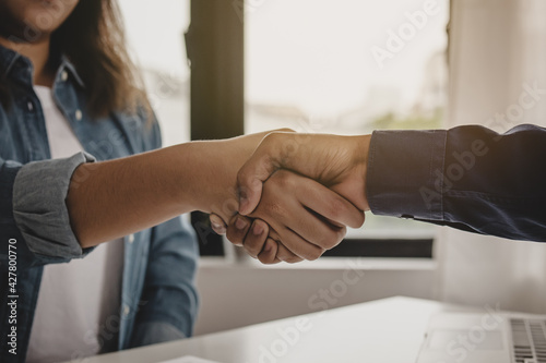 Successful young asian woman, man  partnership, team handshake together at office after project done, good deal. .Happy business people, worker meeting, shaking hands concept..