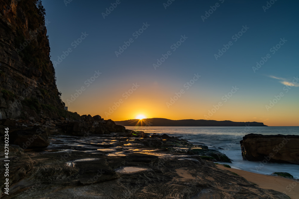 Sunrise seascape with headland and sunburst