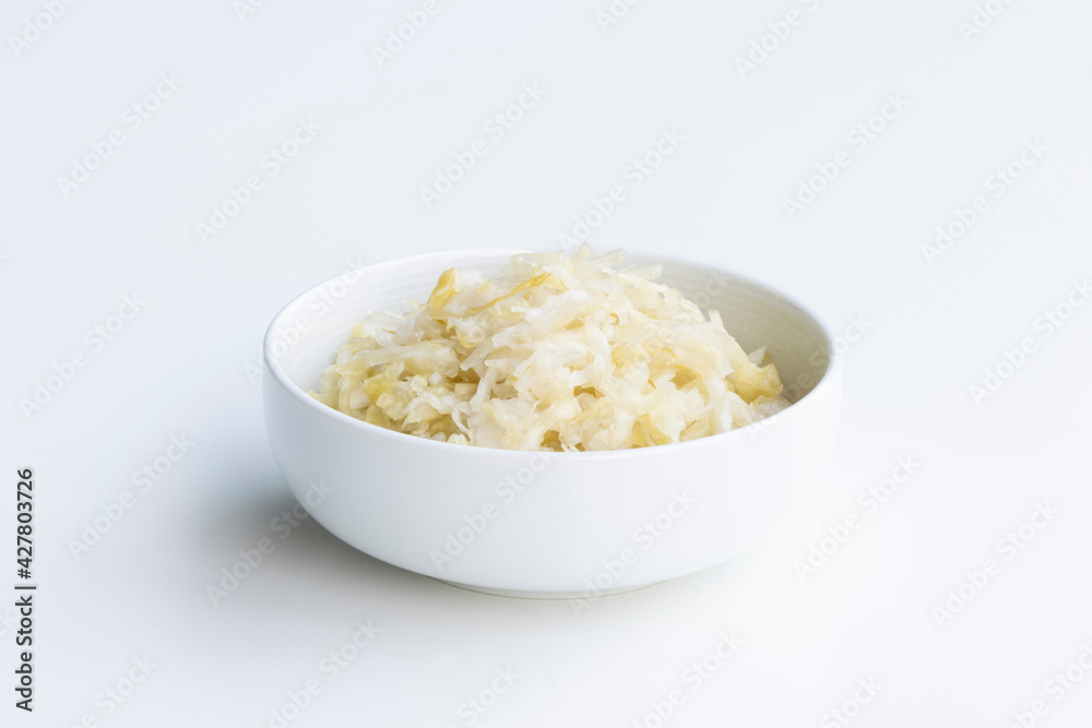 Fresh homemade sauerkraut in a bowl isolated on a white background. Sauerkraut is finely cut raw cabbage that has been fermented by various lactic acid bacteria. Fresh homemade sauerkraut in a bowl isolated on a white background. Sauerkraut is finely cut raw cabbage that has been fermented by various lactic acid bacteria.