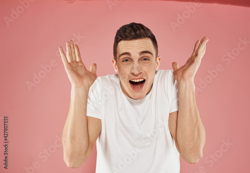 handsome man white t-shirt gesture with hands studio pink background
