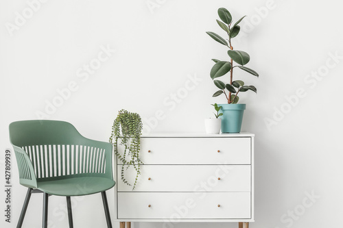 Modern chest of drawers and chair near light wall in room photo