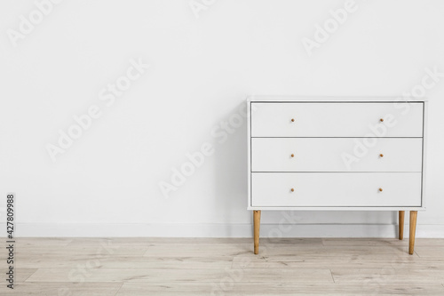 Modern chest of drawers near light wall in room photo