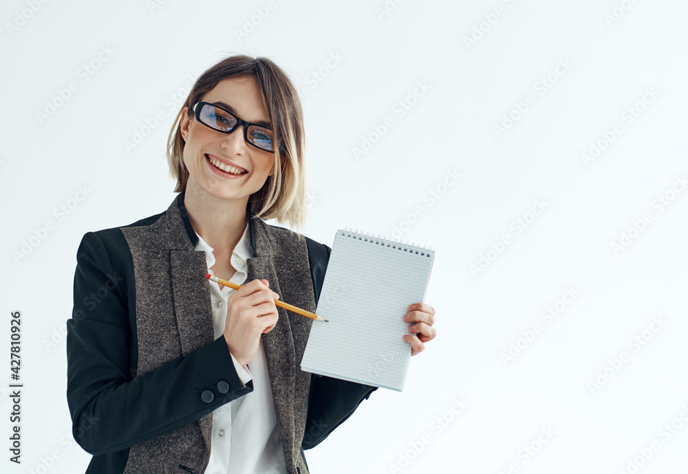 A woman with a notebook and a pen in her hands on a light background business finance suit A woman with a notebook and a pen in her hands on a light background business finance suit