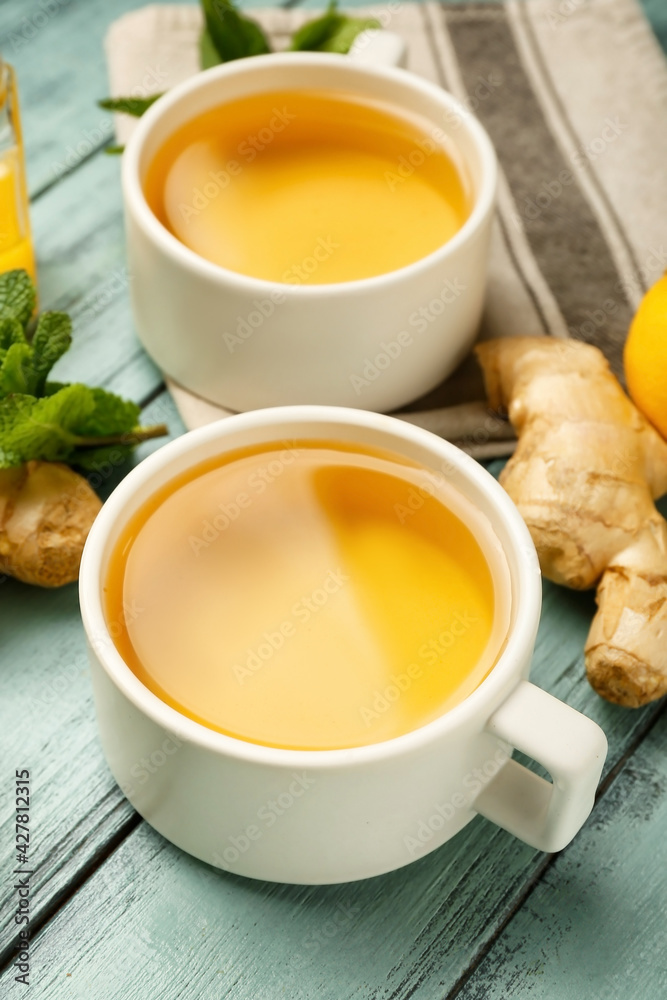 Cups of tea with ginger and lemon on color wooden background Cups of tea with ginger and lemon on color wooden background