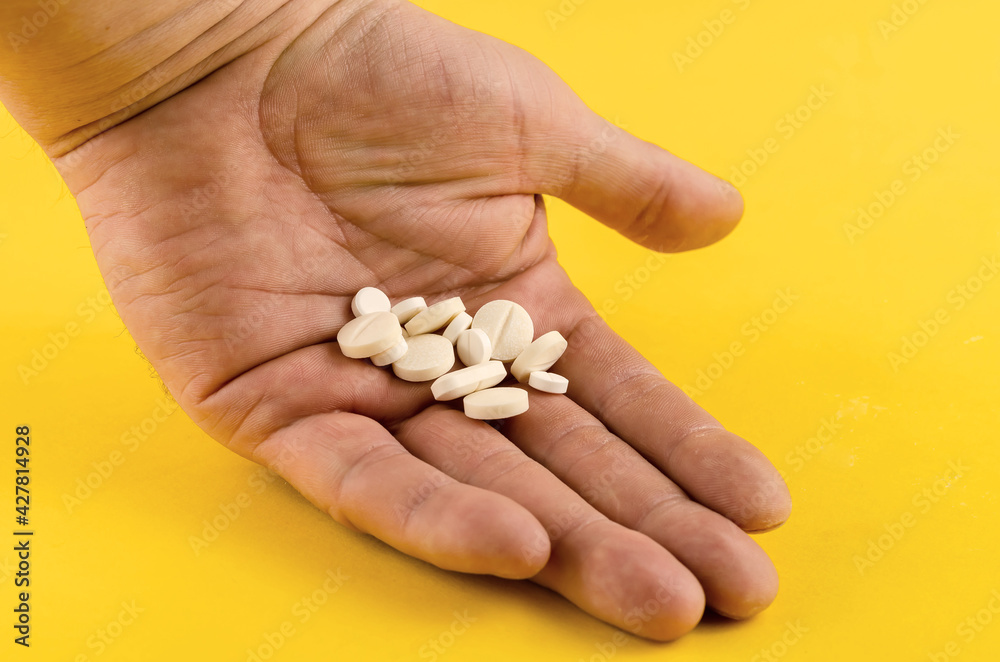 Hand and medical pills on a yellow background. Hand and medical pills on a yellow background.