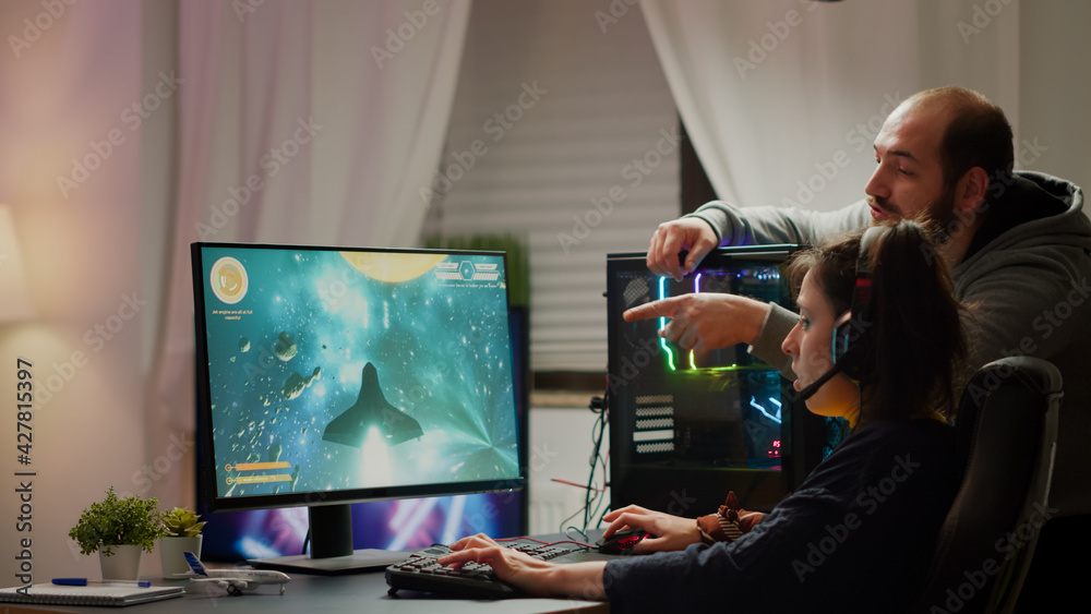 Man gamer teaching his girlfriend playing space shooter video game on RGB  powerful personal computer. Pro cyber woman with headset performing video  games streaming from home during online tournament Photos