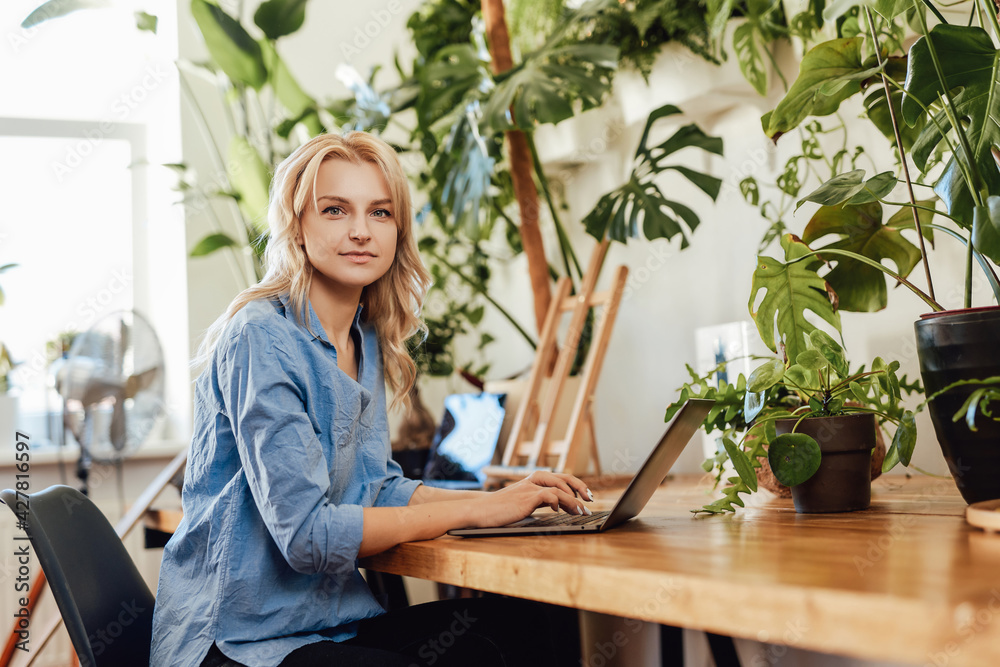 Attractive and pensive female office worker sits at table with a laptop Attractive and pensive female office worker sits at table with a laptop