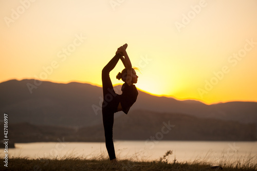 Girl practices yoga in the mountains on the ocean.
