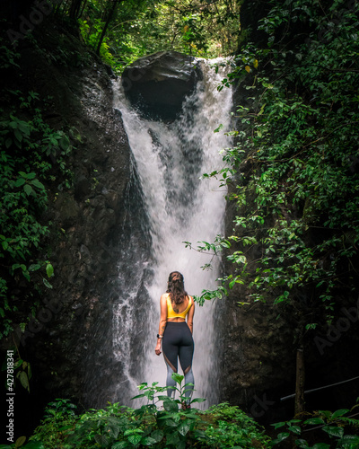 Woman enjoying beautiful waterfall in the jungle