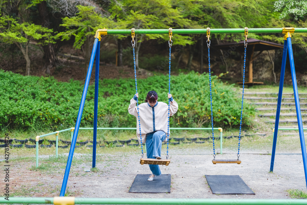 公園のブランコで遊ぶ女性 公園のブランコで遊ぶ女性