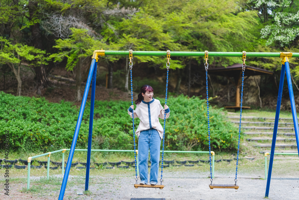 公園のブランコで遊ぶ女性 公園のブランコで遊ぶ女性