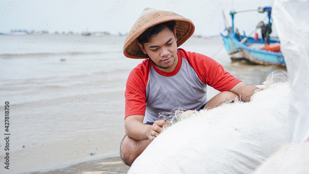 Portrait of a young male fisherman preparing a fishing net in beach