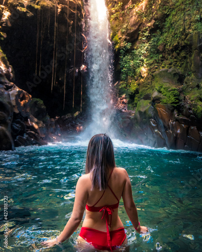 woman in beautiful waterfall with red bikini