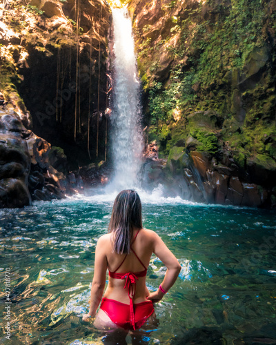 woman in beautiful waterfall with red bikini