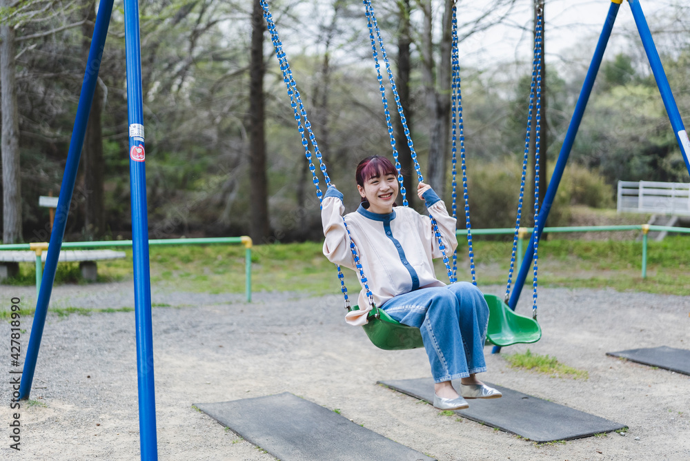公園のブランコで遊ぶ女性 公園のブランコで遊ぶ女性