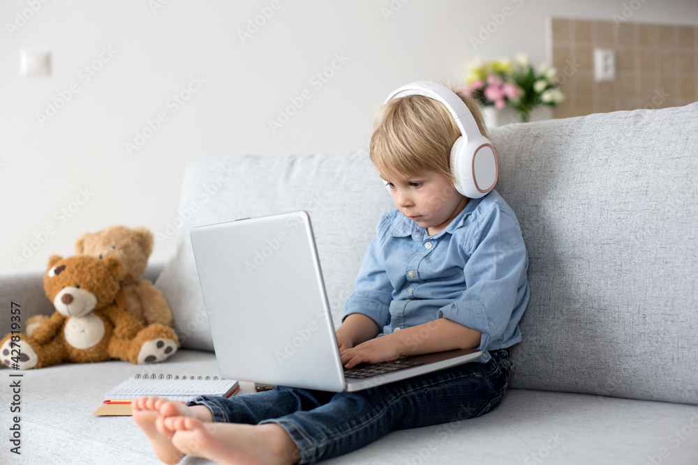 Sweet blond child, boy in casual clothes, woring on computed at home Sweet blond child, boy in casual clothes, woring on computed at home