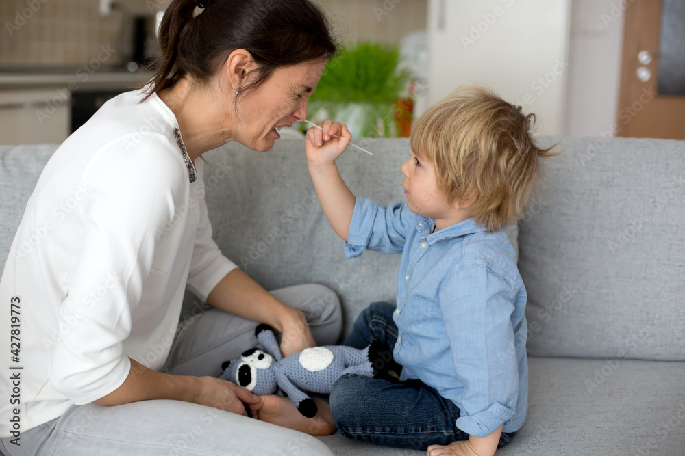 Obraz premium Mother, testing her child for covid at home, making home swab test to prove negative result, child trying to immitate mother