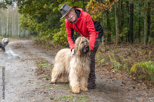 A happy senior man walking with his cute bearded collie dog in the forest. © toranote