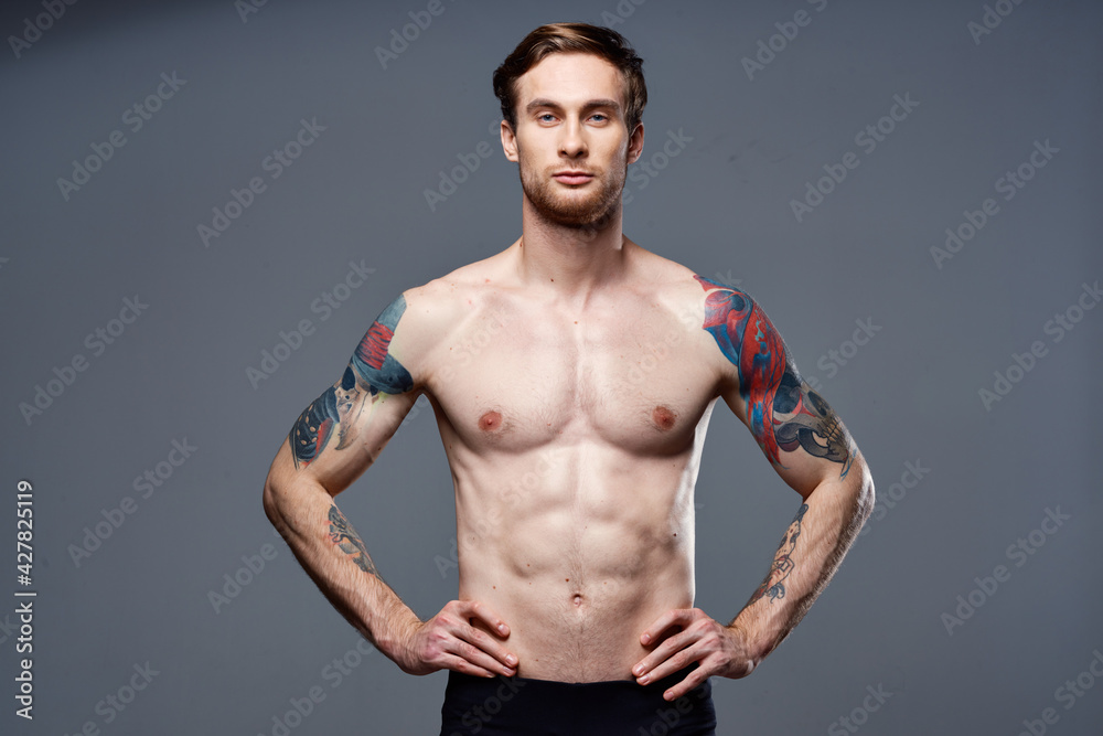 sporty man tattoos on his arms naked torso bodybuilder gray background