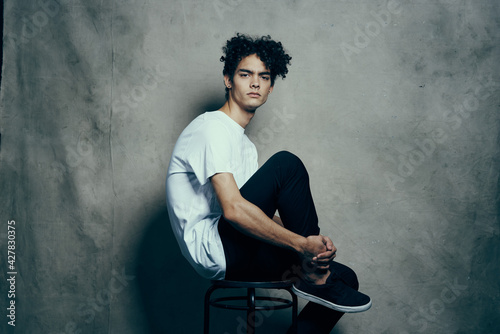 cute guy with curly hair sitting on a chair studio