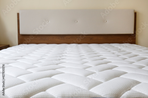 Close up shot of a white orthopedic mattress top side surface pattern on top of the bed. Hypoallergenic foam matress for proper spinal alingment and pressure point relief. Background, copy space. photo