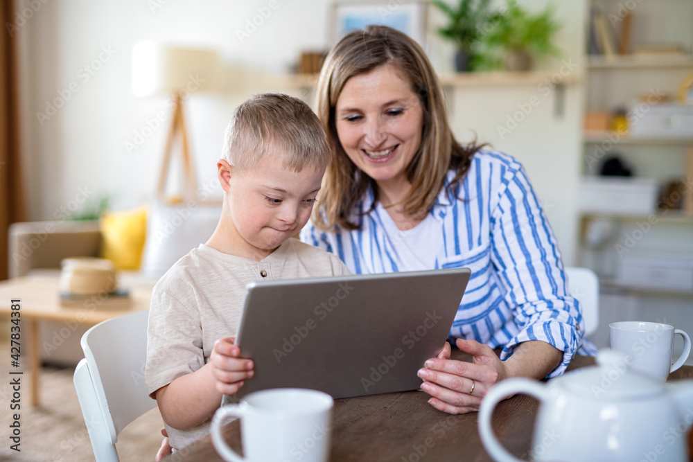 Single mother with down syndrome child at home, using tablet. Single mother with down syndrome child at home, using tablet.