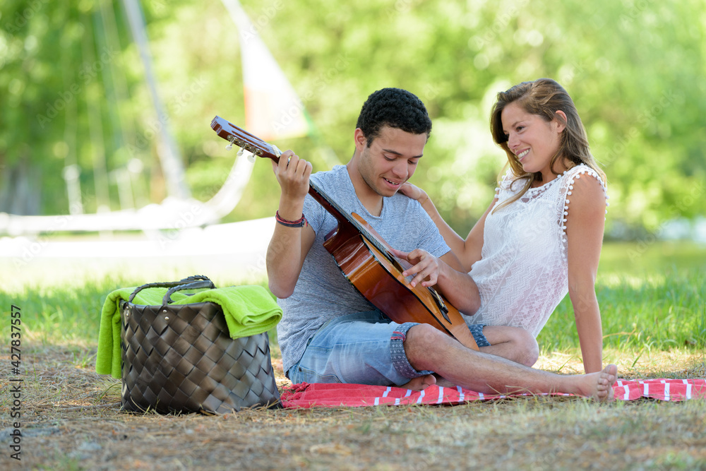 lovely interracial couple sitting with a guitar in park lovely interracial couple sitting with a guitar in park