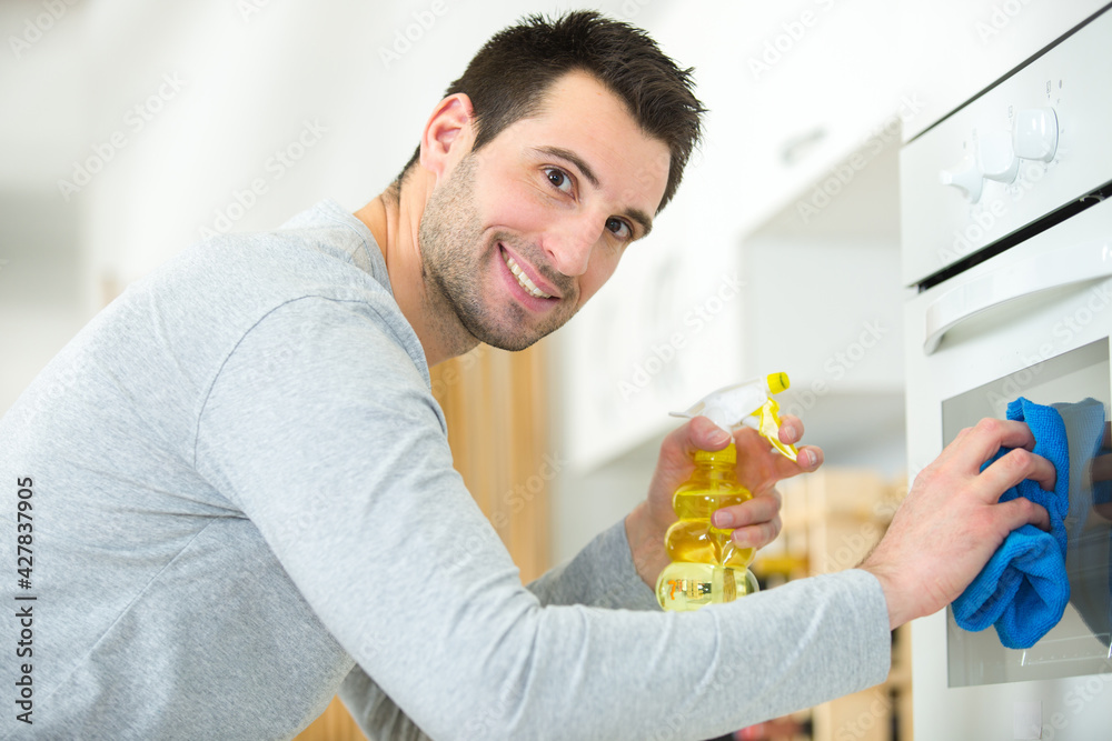 happy young man cleaning oven happy young man cleaning oven