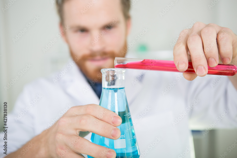 scientist pouring liquid into flask scientist pouring liquid into flask
