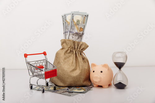 Dollar money bag, ohurglass and a shopping cart photo