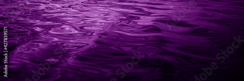 Abstract purple background. Reflection of light on a wavy water surface. Ripples. Beautiful magenta background with copy space for design. Web banner.