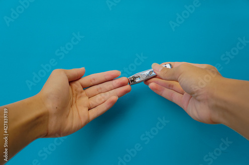 a woman clipping nails with a nail clipper on blue background