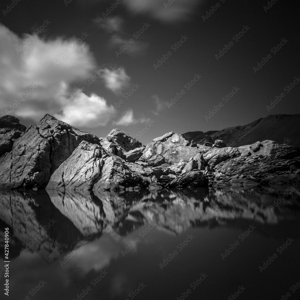 Le Lac des sept couleurs dans les Alpes avec le reflet des rochers et les nuages en noir et blanc