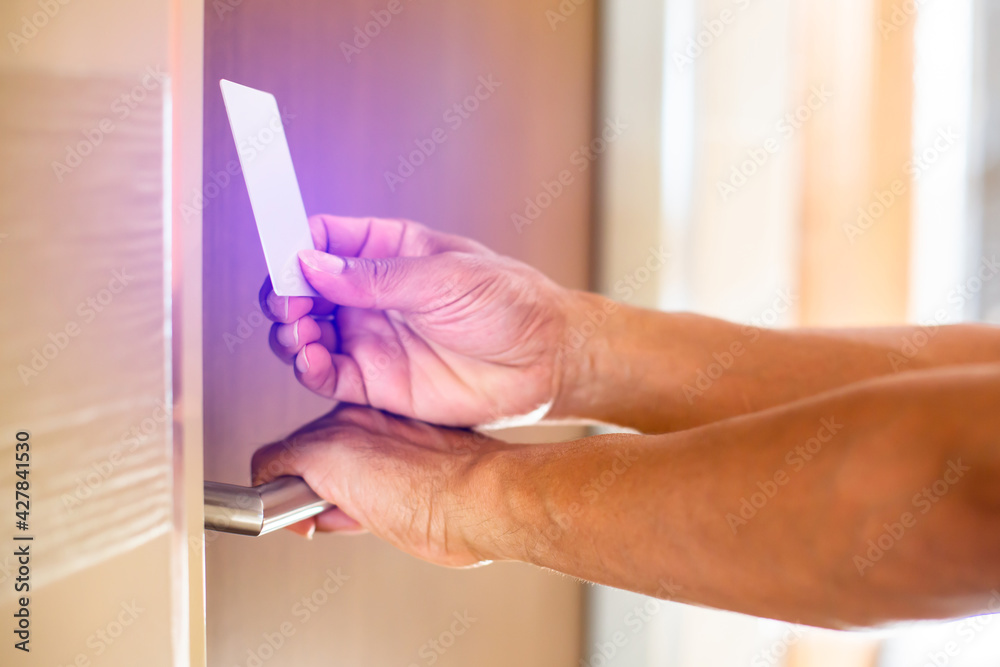 Selective focus to hand holding a key card to unlock door at home or condominium. Door access control.