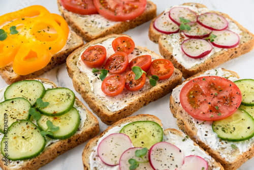 Healthy vegetarian sandwiches with vegetables - yellow pepper, tomato, cucumber and radish. Cream cheese and microgreens
