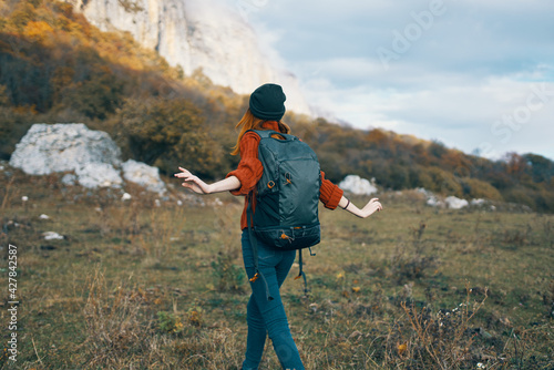 woman with a backpack walks on nature in the mountains in autumn blue sky rocks landscape