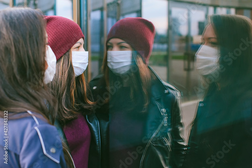 Close-up portrait of girls with medical masks. Against the background of a glass building with reflections. Concept on the topic of viros.