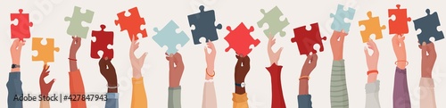  Group of multi-ethnic business people with raised arms holding a piece of jigsaw. Colleagues of diverse races and culture. Cooperate and collaborate. Concept of teamwork and success photo