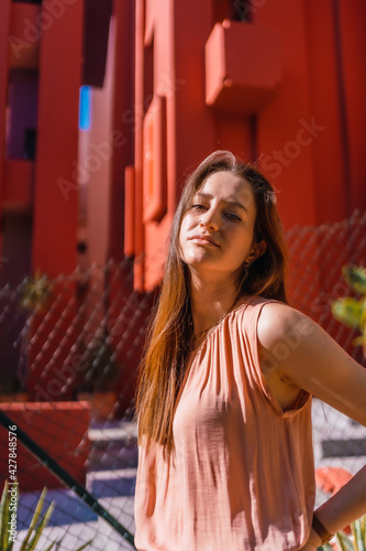 Young caucasian man in a salmon colored t-shirt and white pants in a beautiful colored houses