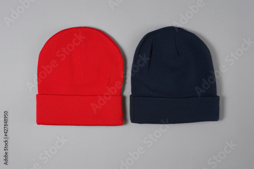 Top view of dark blue and red hipster beanie hats laid out horizontally isolated over gray background photo