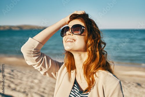 attractive woman in sunglasses on the sand near the sea in the mountains