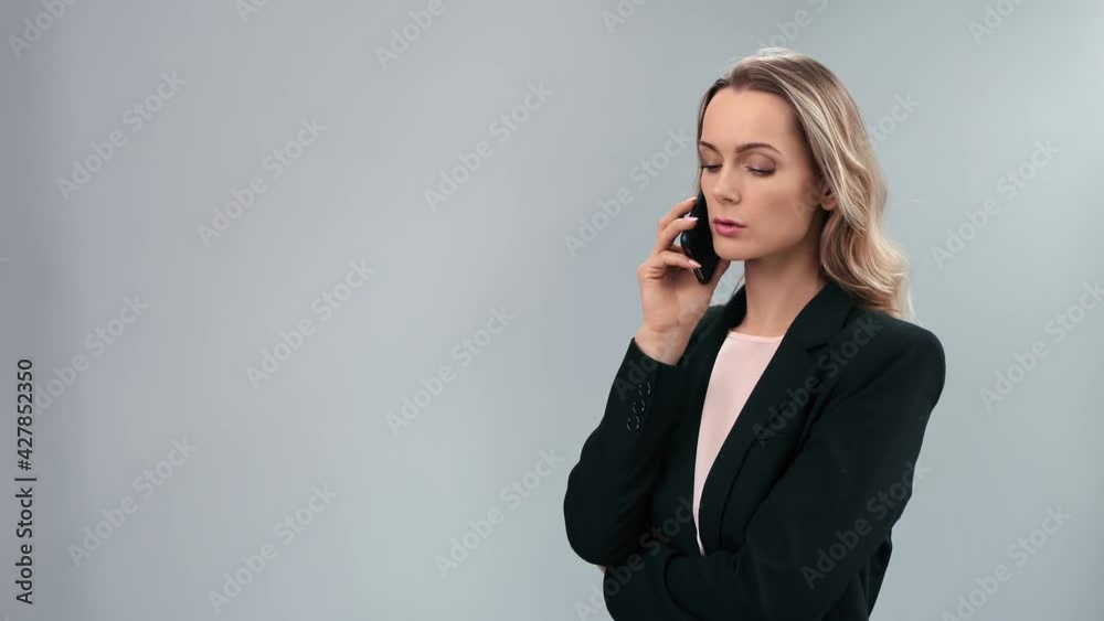 Confident female boss talking smartphone isolated on gray. Shot on RED Raven 4k Cinema Camera Confident female boss talking smartphone isolated on gray. Shot on RED Raven 4k Cinema Camera