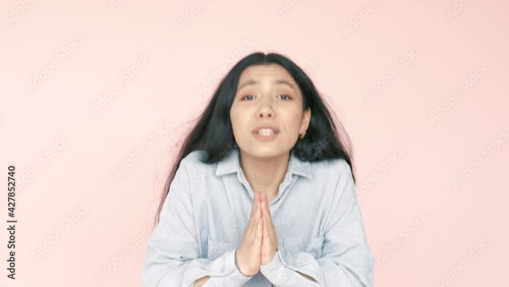 Worried unhappy hispanic latin woman folding hands in pray, pleading forgiveness, beseeching and apologizing, looking at camera with guilty expression. Indoor isolated on pink background Worried unhappy hispanic latin woman folding hands in pray, pleading forgiveness, beseeching and apologizing, looking at camera with guilty expression. Indoor isolated on pink background