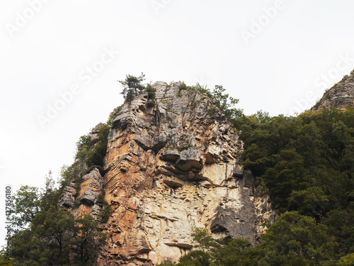 Steep cliffs covered with green vegetation against the backdrop of a white cloudy sky