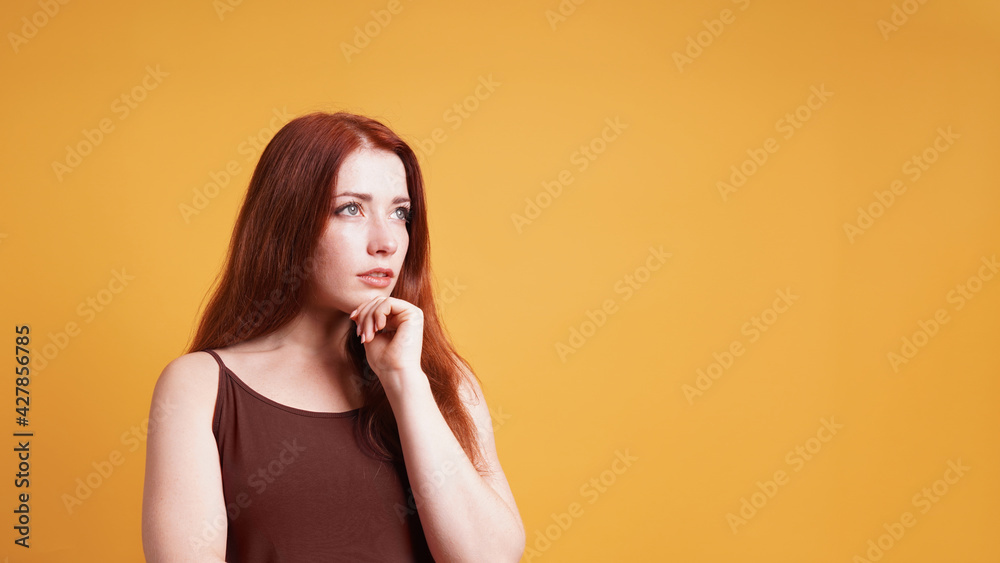 contemplating young woman thinking with hand on chin gesture looking up to copy space contemplating young woman thinking with hand on chin gesture looking up to copy space