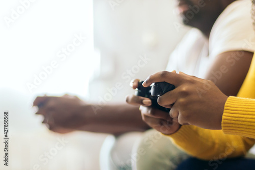two People playing video game at home. Close-up on the gamepad. side view