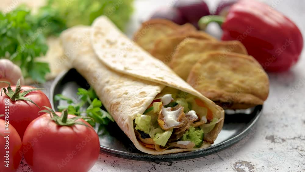 Traditional Turkish doner kebab in a wrap served with fresh ingredients and deep fried dumplings